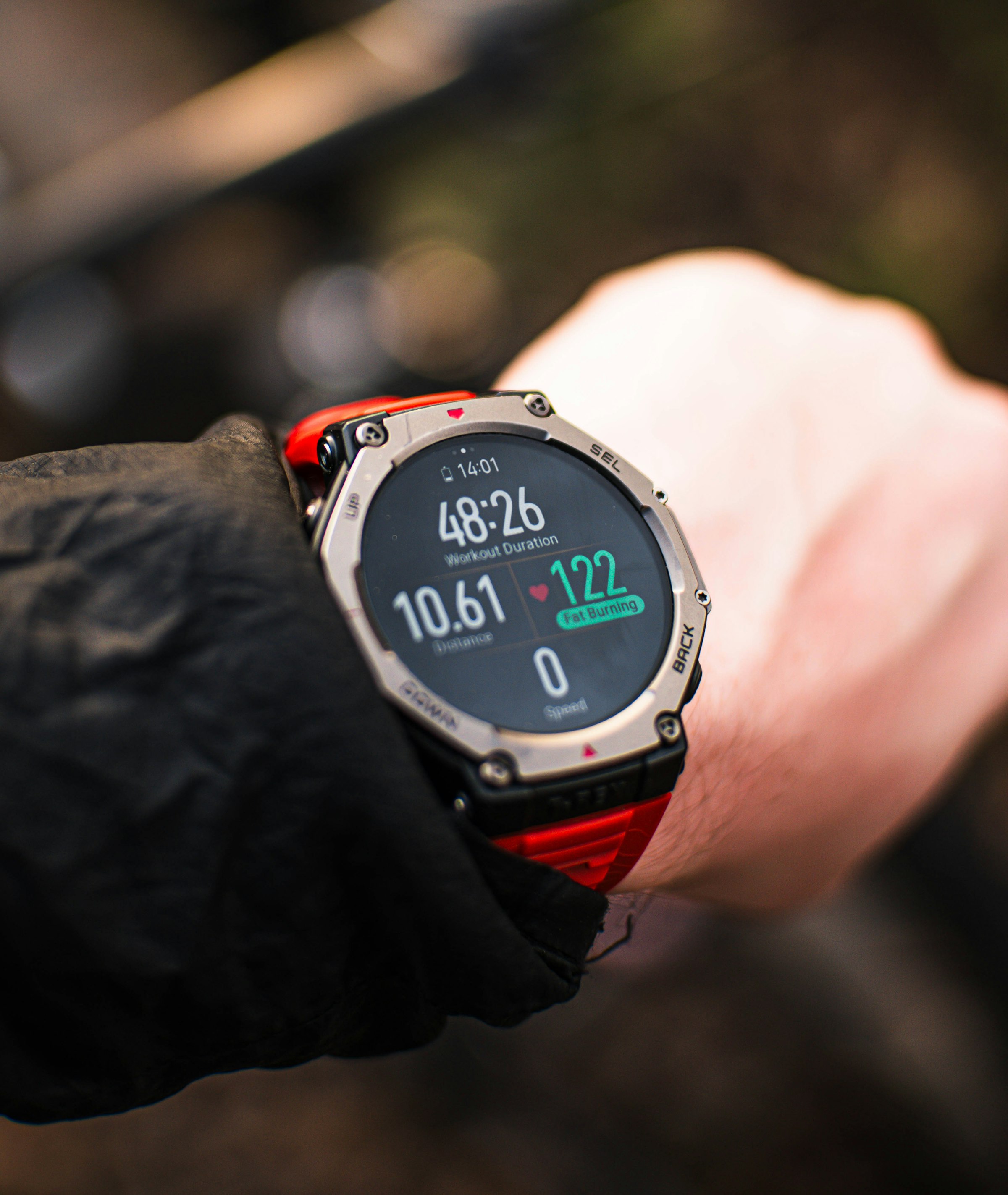 Close-up of a person checking a rugged GPS sports watch mid-workout, showing workout duration, distance, and heart rate.